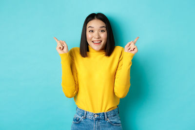 Portrait of smiling young woman against blue background