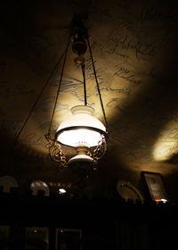 Low angle view of illuminated light bulb hanging against sky