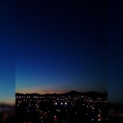 Illuminated cityscape against clear sky at night