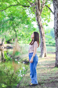 Side view of woman standing on tree trunk