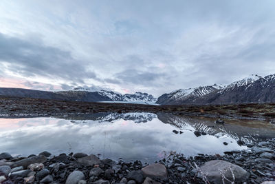 Scenic view of lake by snowcapped mountains against sky