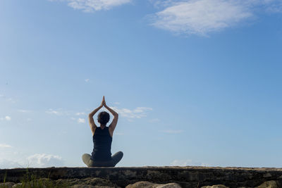 Woman doing yoga against blue sky