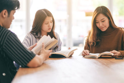 Young woman reading book on table