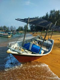 Ship moored on beach against sky