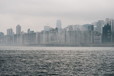 Sea by buildings in city against sky