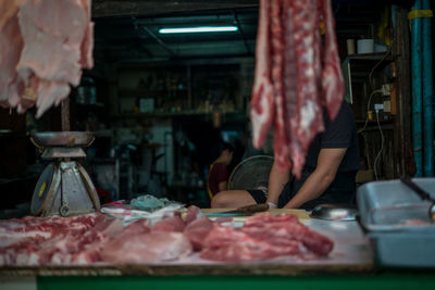 Midsection of man sitting at butcher shop