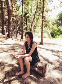 Portrait of young woman sitting on tree trunk