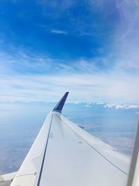 Airplane flying over clouds against blue sky