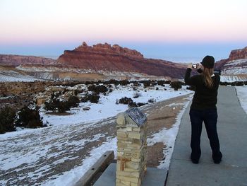 Woman photographing on snow covered landscape