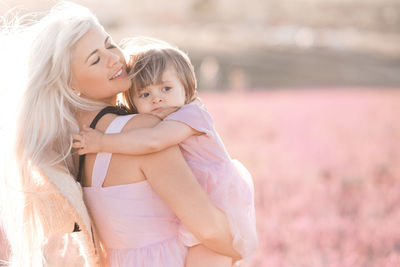 Happy smiling woman holding baby girl 2-3 year old playing in flower lavender field outdoor