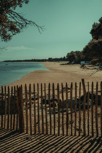 Wooden posts on beach against sky