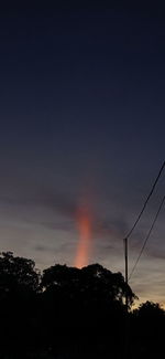 Silhouette trees and electricity pylon against sky during sunset