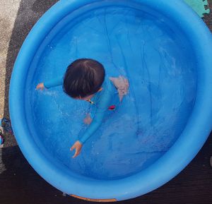 High angle view of boy playing in inflatable wading pool