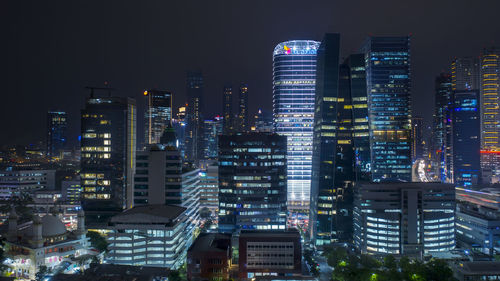 Illuminated buildings in city against sky at night