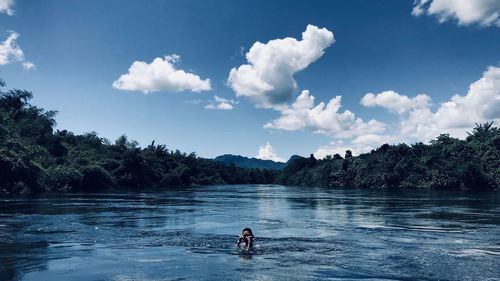 Man surfing in water against sky