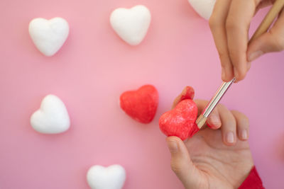 Cropped hands of woman holding heart shape against white background