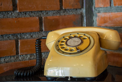 Close-up of telephone against brick wall