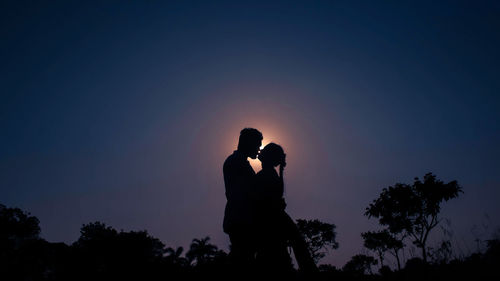 Silhouette couple standing against sky during sunset