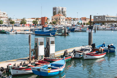 Sailboats moored in harbor against buildings in city