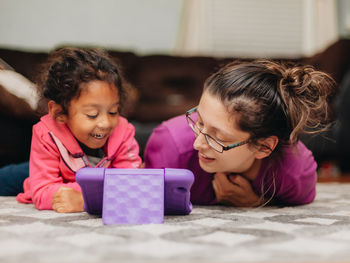 Mother and mixed race daughter at home having fun using a learning tablet computer 