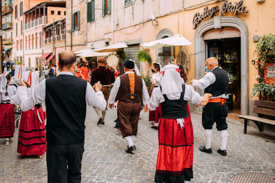 Rear view of people walking on street in city