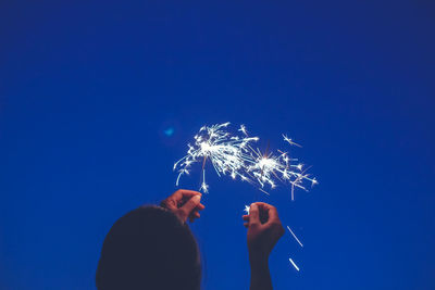 Low angle view of firework display against blue sky