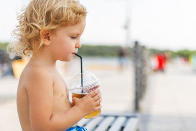 Young woman drinking water while standing outdoors