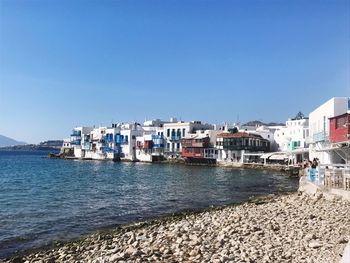 View of town by sea against clear blue sky