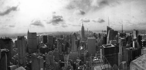 Aerial view of buildings in city against cloudy sky