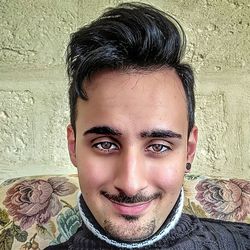 Close-up portrait of smiling young man against wall