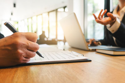 Midsection of man using smart phone on table