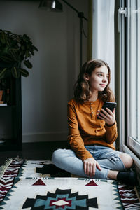 Young woman using mobile phone at home