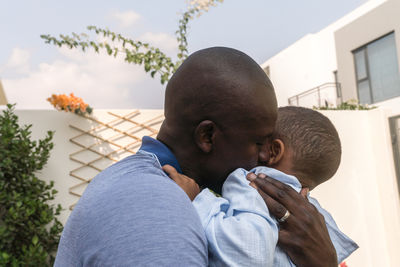 Father holding his mixed race son in his hands and kissing him