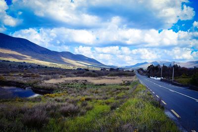 Road leading towards mountains against sky