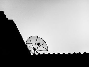 Low angle view of silhouette communications tower against clear sky