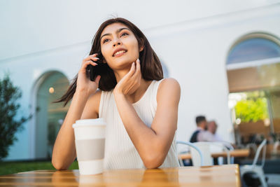 Portrait of a smiling young woman sitting at table