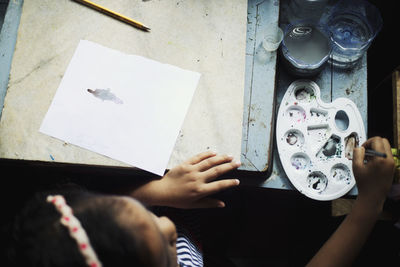 High angle view of girl painting on paper