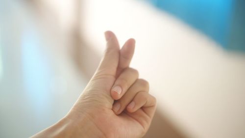 Close-up of woman snapping fingers against blurred background