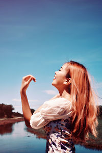 Side view of young woman against sky