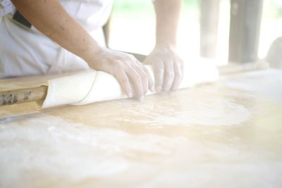 Midsection of chef rolling dough at commercial kitchen