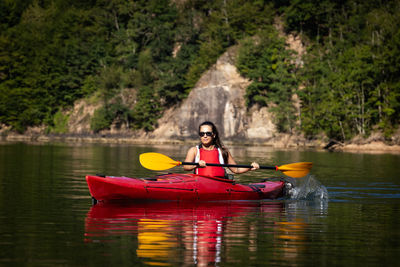 Woman rowing boat on lake against trees