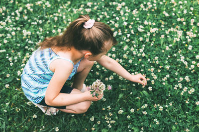 Rear view of girl with flowers on field