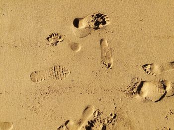 Directly above shot of footprint on sand during sunny day