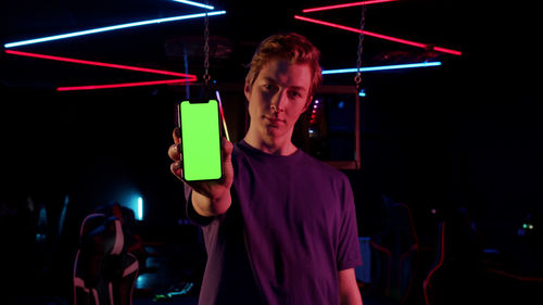 Portrait of man using mobile phone while sitting in darkroom