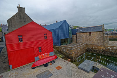 Houses by building in city against sky