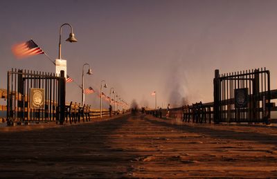 Illuminated street lights against clear sky during sunset