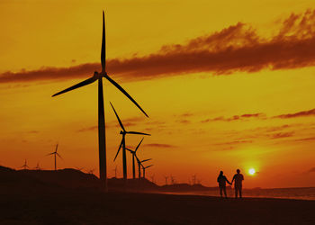 Silhouette of wind turbines on land during sunset