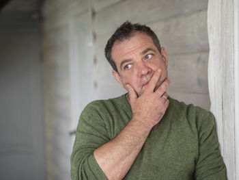 Thoughtful mature man leaning on wall at home