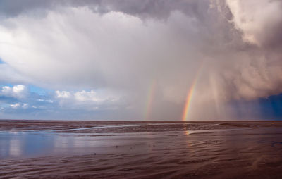 Scenic view of rainbow over sea against sky