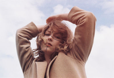 Low angle portrait of woman with face paint standing against sky